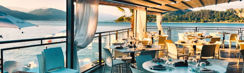 Tavoli all'aperto di un ristorante affacciato sull'acqua, al tramonto