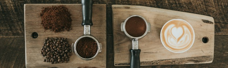 Chicchi di caffè, portafiltro e tazza con latte art su un tavolo di legno