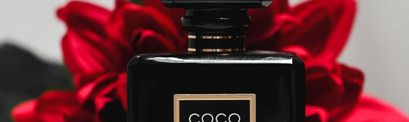 Flacone nero di profumo accanto a una rosa rossa