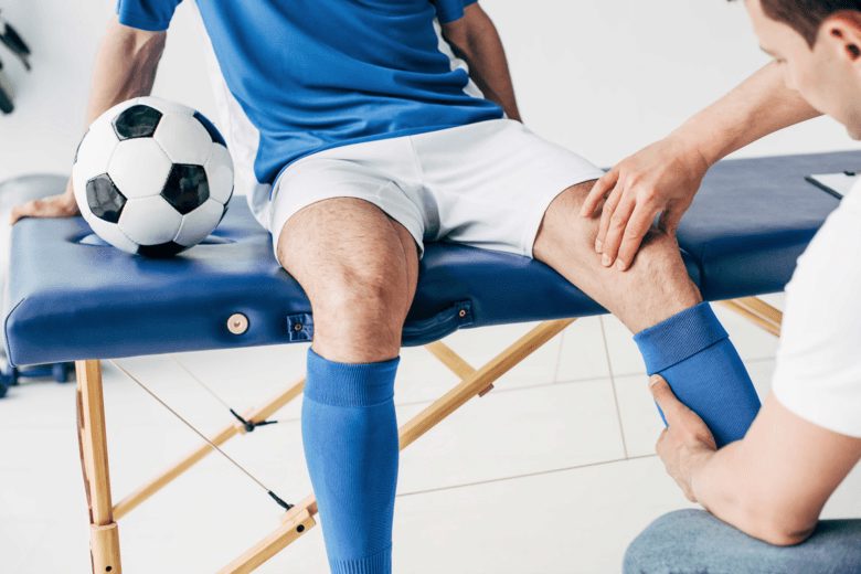 Massaggio sportivo alla gamba di un calciatore