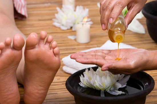 Olio versato sulle mani durante un massaggio ai piedi