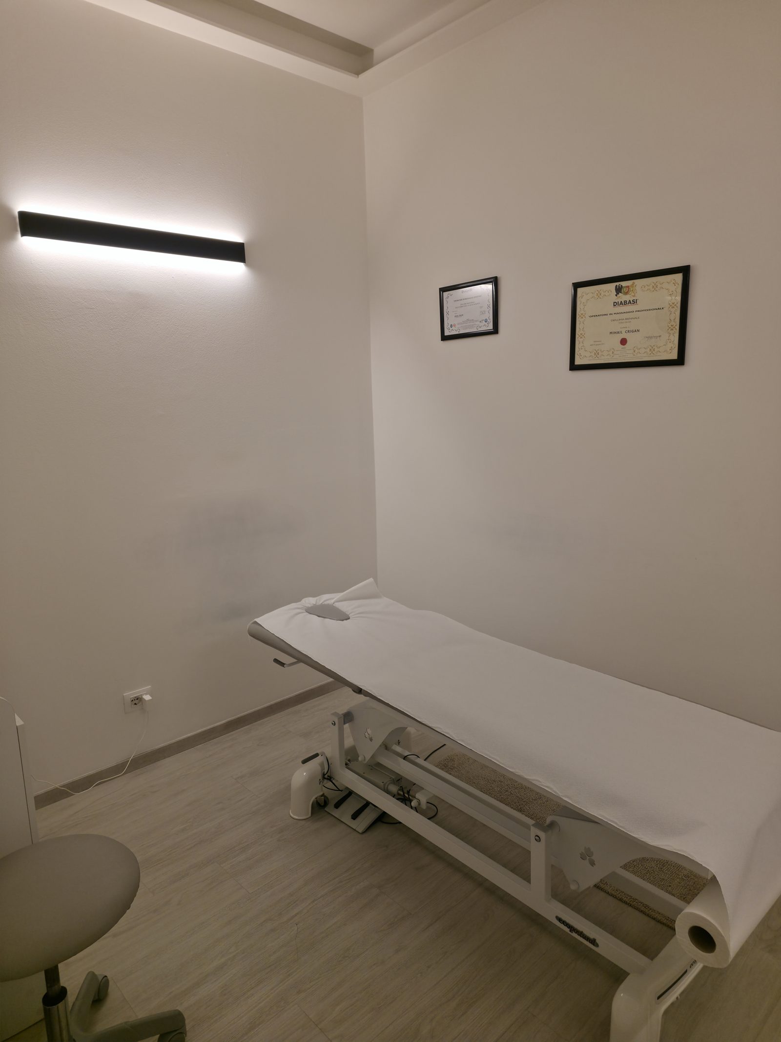 Lettino professionale con certificati al muro nello studio Crigan Massaggi a Torino